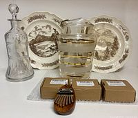 Entire lot showing decanter, two plates, gold-striped pitcher, four thumb harps (three boxed, one unboxed)