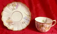 Teacup front and scalloped saucer reverse showing floral pattern and gold accents