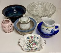 Group shot showing seven ceramic and glass pieces including berry bowl, clear ribbed dish, lidded jar, candle holder, small bowls, creamer and Aynsley candy dish