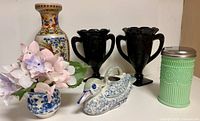 All six decorative items arranged together: two black glass vases, Asian motif vase, blue-white mini vase with silk flowers, ceramic duck, jadeite sugar shaker