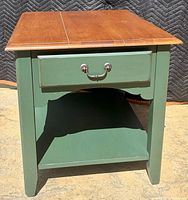 Front view of cherry top side table with green sides, single drawer, lower shelf
