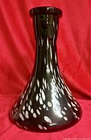 Full view of black and white speckled Fumari Snow hookah base against red background