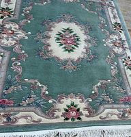 Full view of rug showing aqua field, ivory border, central medallion, fringe