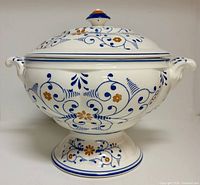 Footed ceramic soup tureen with lid showing hand painted blue scrolls and orange flowers