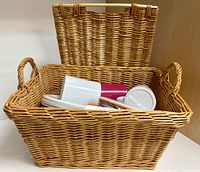 Rattan picnic basket open showing plates, tumblers and utensils inside