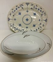 Three of the five platters: blue floral platter, and two white platters with silver rim and grey leaf design