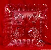 Top view of pressed glass square tray showing feather motif and scalloped rim