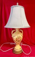 Full view of ceramic lamp with shade, finial, cord and base visible