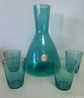 teal-green glass decanter centered, four matching tumblers arranged around