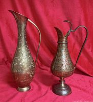 Two etched brass pitchers, one 10" plain brass, one 8" enamelled brass on pedestal