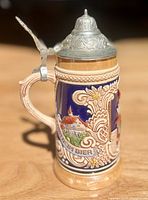 Full view of beer stein showing chalet relief, handle, and pewter lid closed