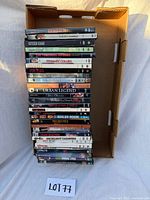 Stack of approximately 29 DVDs in open cardboard tray