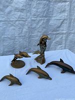 All five brass dolphin figurines displayed