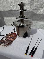 Full view of fountain, power cord, chocolate packet, three forks
