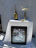 Overall lot: two lamps on table and framed print leaning beneath