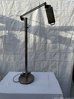 Full view of metal floor lamp showing height, arm, base and cord