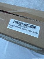 Sealed shipping box with product label showing brand, size, rooms, condition