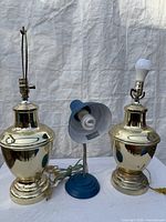 Two brass table lamps and blue desk lamp front view