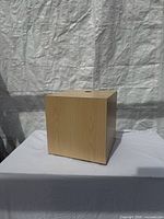 front view of cube pedestal showing wood grain and top cord hole