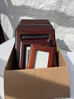 Box containing stacked brown and black picture frames