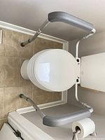 Top view of safety rail installed on toilet showing padded arm rests and clamp mount