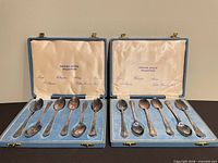 Two open cases showing 12 spoons in fitted interiors