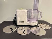 Food processor front view with four discs displayed
