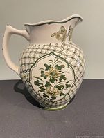 Left side view of ceramic watering vase showing handle and painted motifs