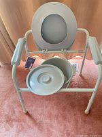 Front view of commode showing seat open, bucket and lid