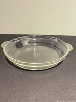 Oblique view of clear glass pie plate showing side handles and embossed center mark