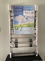 Front view of folded Greenway stainless steel drying rack in packaging showing product label and shoe holder clips