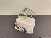 Angled view of clear glass walrus on stone base