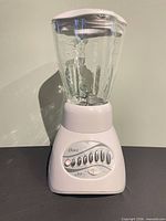 Front view showing Oster logo, 12-button control panel, glass pitcher