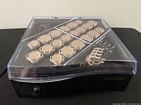 Closed view of heating base with clear lid showing 20 beige rollers and clips
