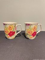 Front view of both porcelain teacups showing Country Rose floral pattern and loop handles