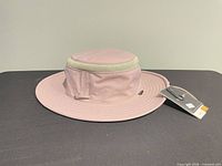 Side profile of pink Tilley boonie hat showing brim, mesh crown band and hang tags