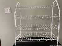 Front view of white coated metal 4-tier wire shoe rack showing all shelves and frame