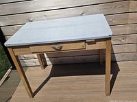 Full view of table showing enamel top, drawer, wood legs