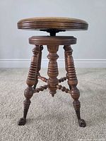 Full view of antique swivel piano stool with turned legs and claw feet