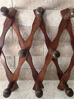 Front view of expanded wooden accordion peg rack showing eight pegs and dark brown stain