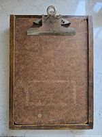 Front view of vintage clipboard showing wood frame, masonite board, metal clip