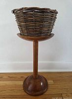 Full view of wood pedestal stand with empty wicker basket