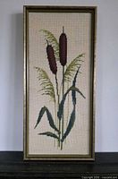 Full view of framed needlepoint showing cattail design and frame