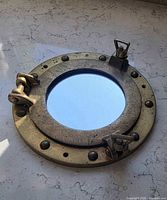 Front view of brass porthole mirror showing latches and mirror glass
