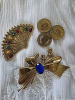 All three brooches: fan, coin trio, bow with blue stone