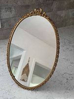Front view of brass oval mirror standing on countertop