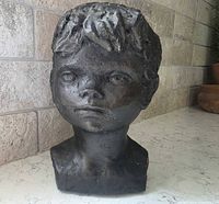 Front view of dark composition bust of young boy
