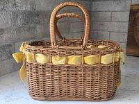 Side view of woven wood basket purse showing yellow velvet ribbon and handles