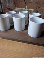 Six white Browne coffee mugs standing upright
