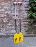 Full view of both paddles leaning against brick wall